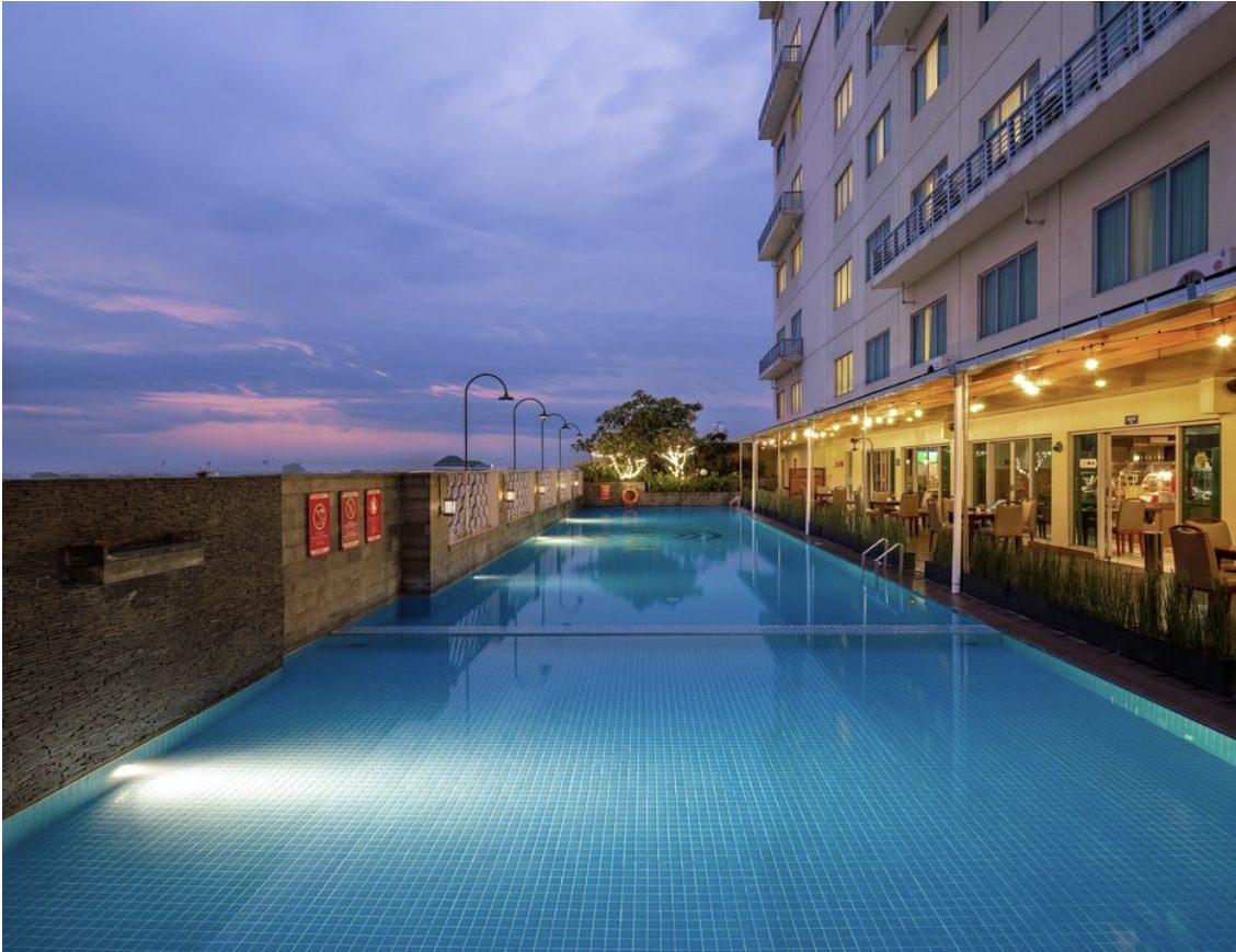 Hotel rooftop pool lined with blue mosaic at dusk