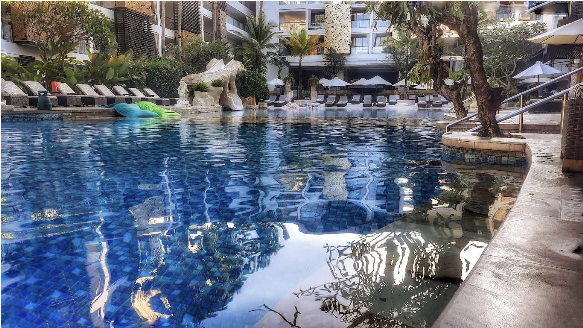 Resort pool with blue mosaic and reflections of palm trees